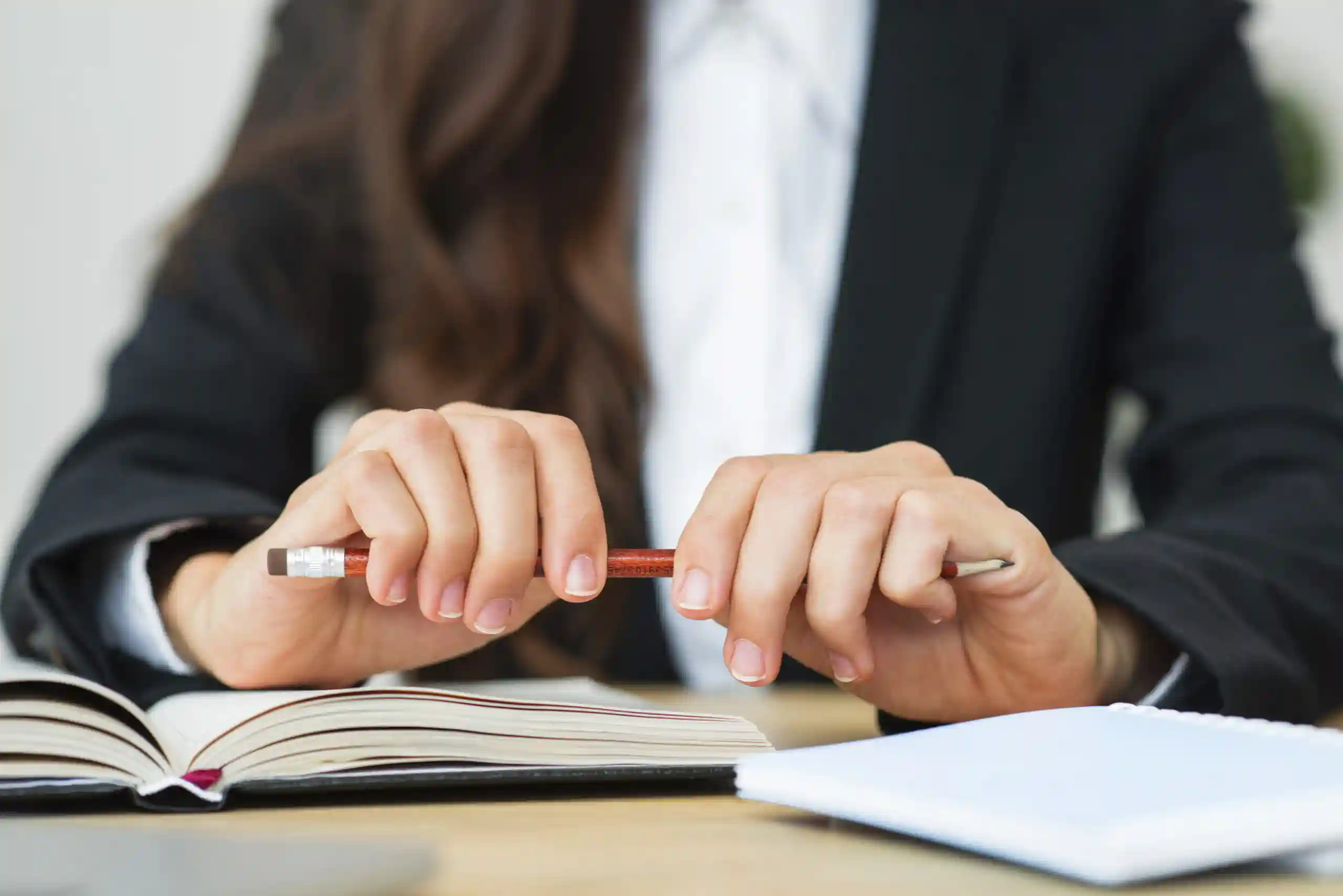 close-up-businesswoman-holding-red-pencil-her-two-hands-desk-scaled